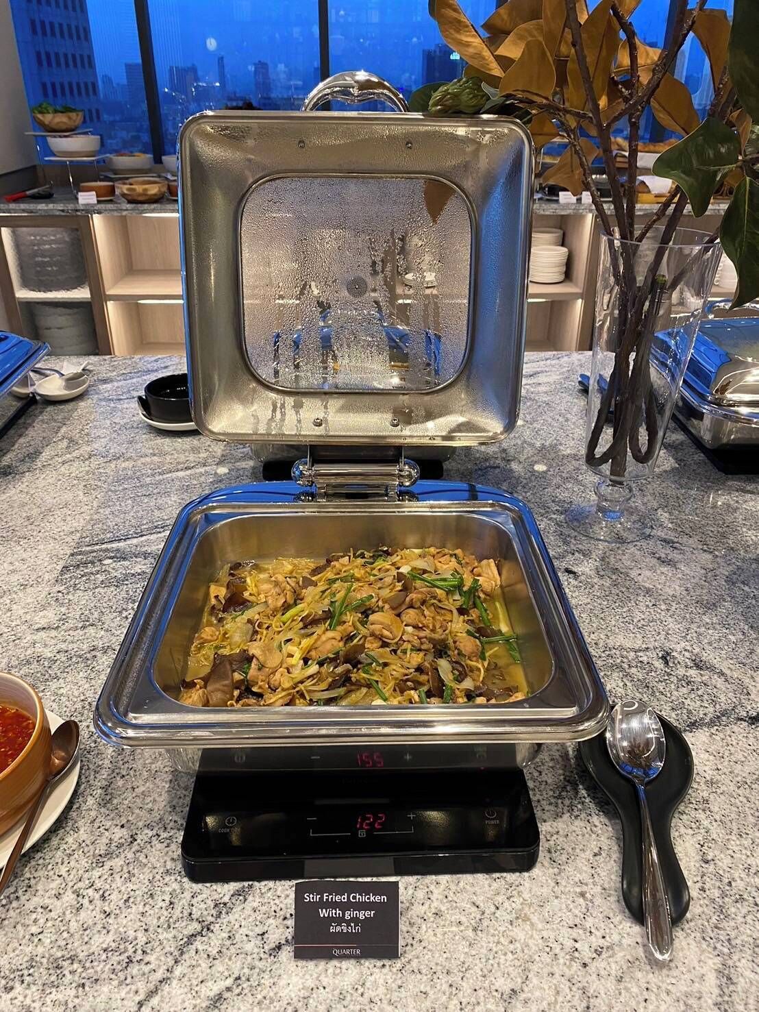 Ein Buffet mit einer gebratenen Hähnchenspeise, die mit Ingwer zubereitet wurde, auf einer digitalen Waage.