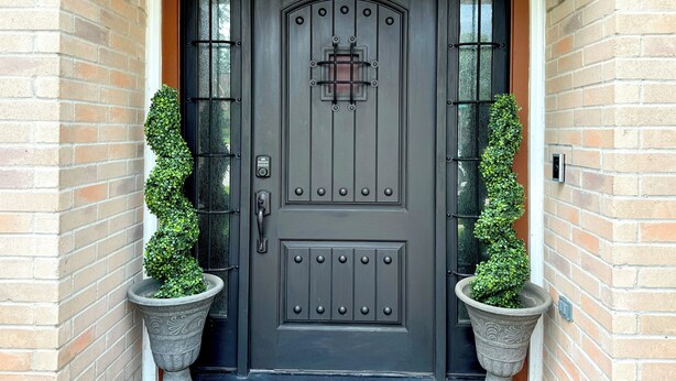 A dark wooden front door with a keypad lock, flanked by two potted plants. - Modern, exotic 5br, pool, hot-tub near Woodlands (Spring)