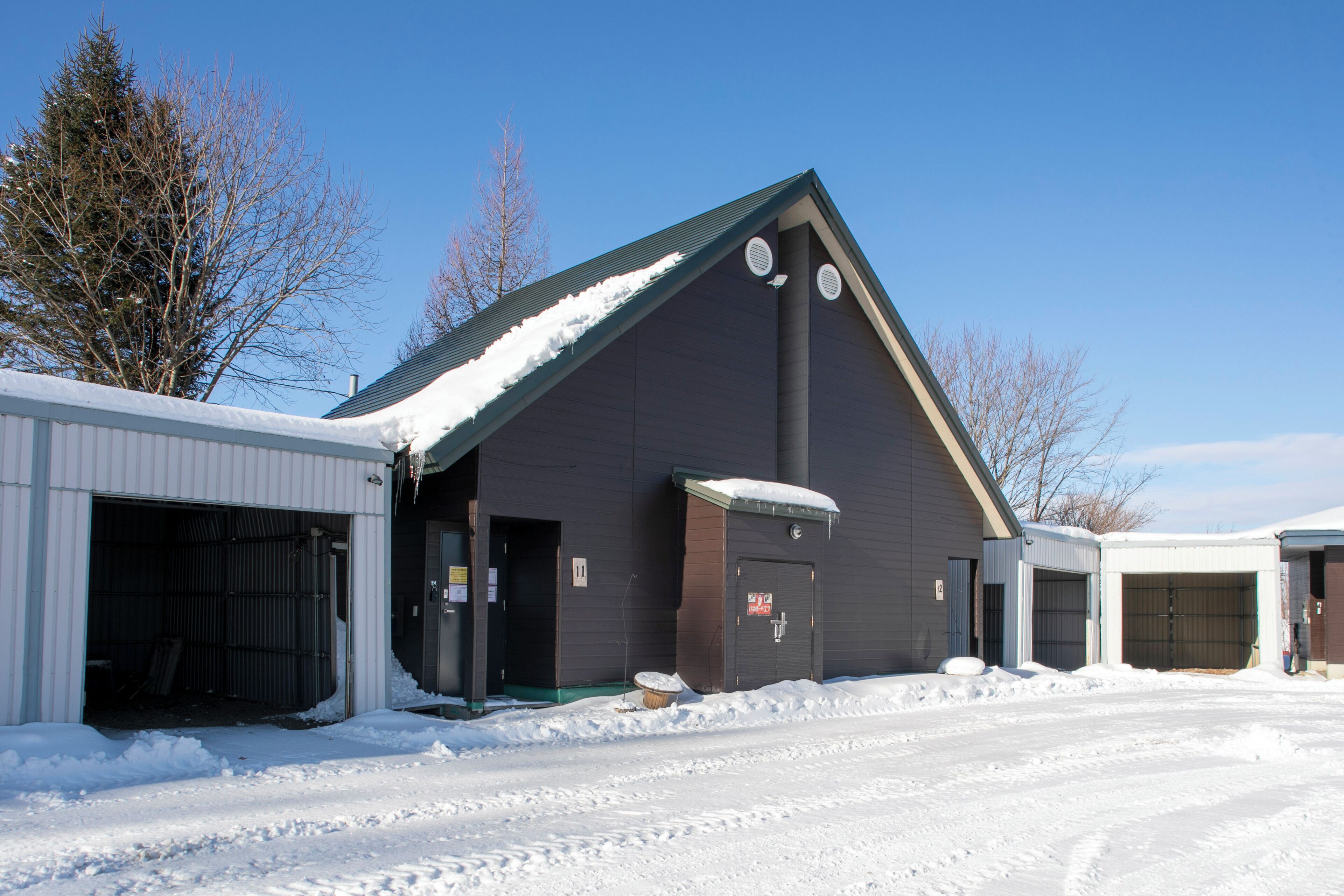 A building with multiple garage doors and a snow-covered roof.