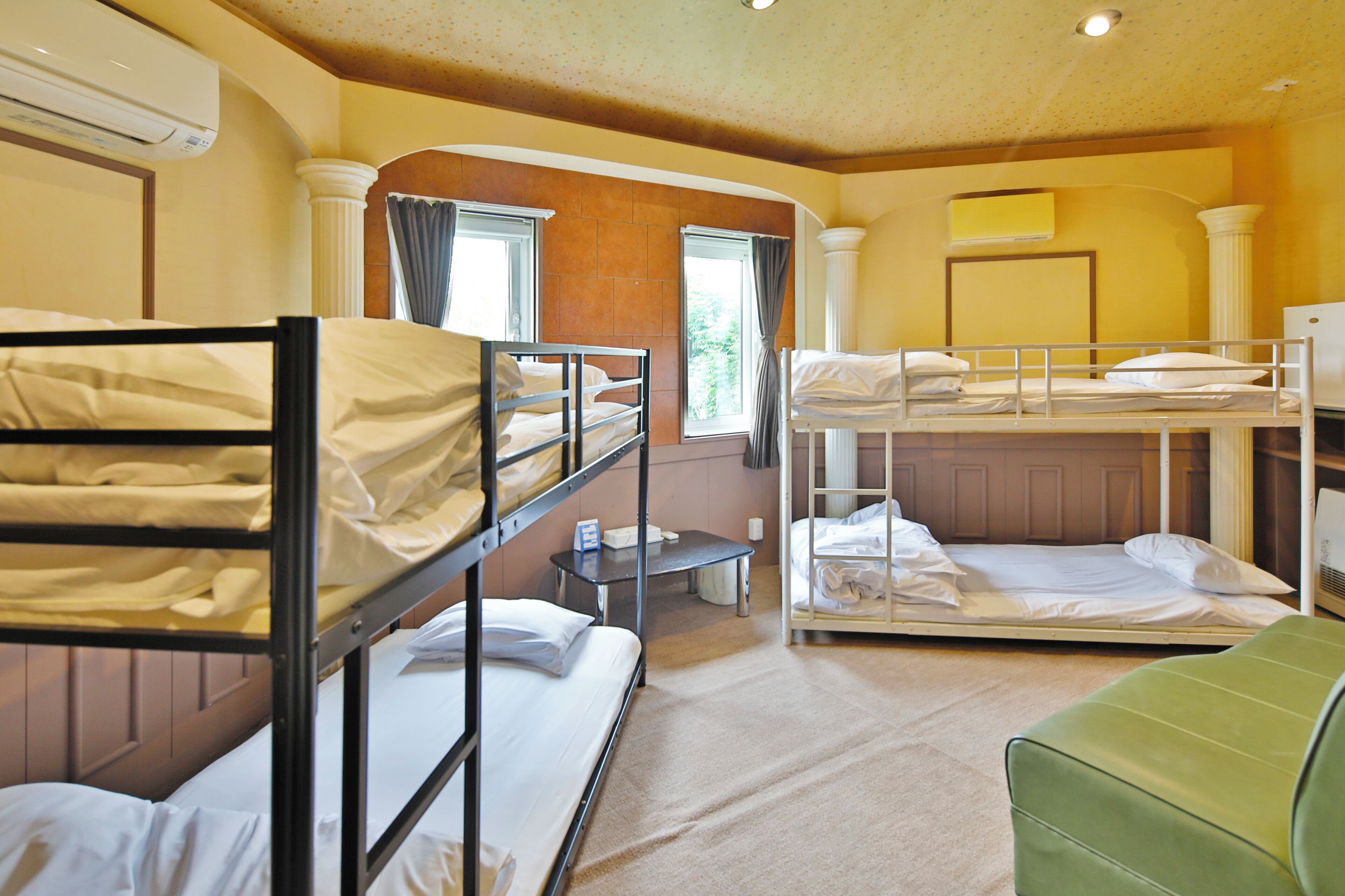 A hotel room with bunk beds, a green armchair, and a small table.
