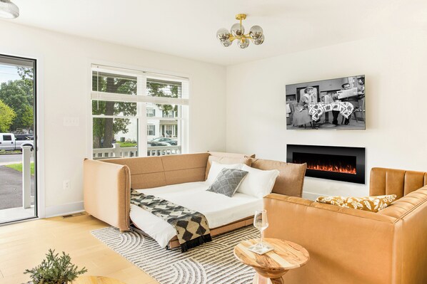 Une chambre moderne avec un canapé-lit, une cheminée et une grande fenêtre.