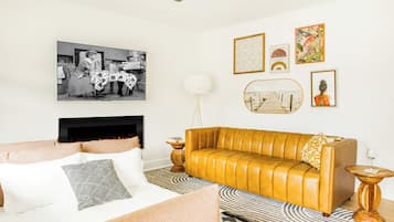 Una sala de estar con sofá, chimenea y obras de arte en las paredes.