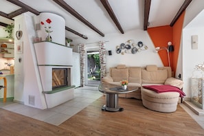 A living room with a fireplace, a sofa, a coffee table, and a dining area with a wooden table and chairs. - Holiday Home 'In Oerrel With Pool' with Private Pool, Private Terrace and Wi-Fi (Munster)