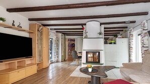 Una sala de estar con televisor, muebles de madera, chimenea y sofá.