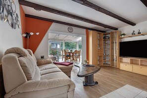 A living room with a sofa, a coffee table, a TV, and a dining area with chairs and a table. - Holiday Home 'In Oerrel With Pool' with Private Pool, Private Terrace and Wi-Fi (Munster)