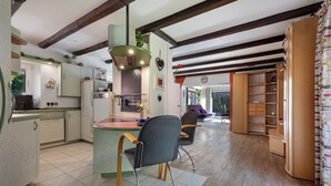 Una cocina con isla central, vigas de madera y un comedor con sillas.