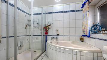 Une salle de bain dotée d’une douche à parois de verre, d’une baignoire et d’une roue décorative.