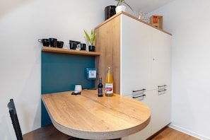 Une cuisine avec une table en bois, un meuble et une plante en pot.