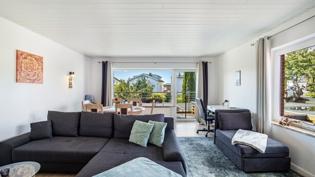 Een moderne woonkamer met een bank, een klein tafeltje en een raam met gordijnen.