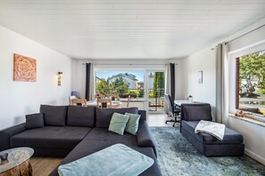 Een moderne woonkamer met een bank, een klein tafeltje en een raam met gordijnen.