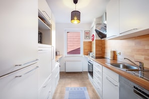 Eine moderne Küche mit weißen Schränken, einer Holz Arbeitsplatte, einem Einbauofen und einem Geschirrspüler von Siemens.