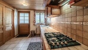 Una cocina con armarios de madera, estufa y ventana con cortinas.