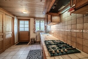 A kitchen with wooden cabinets, a stove, and a window with curtains.