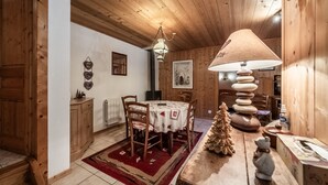 Un interior de madera con una mesa de comedor, sillas, una lámpara, un pequeño árbol de Navidad y una figura de un oso.