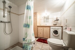 Une salle de bain équipée d’une douche, de toilettes, d’un lave-linge et de meubles en bois.