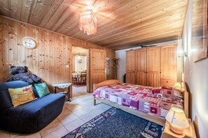 Et rum med træpaneler, en seng, en sofa, et lille bord og en stol.