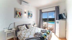 Ein modernes Hotelzimmer mit Bett, Schreibtisch, Fernseher und Blick auf einen Pool.