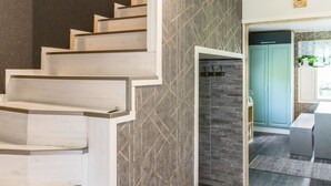 Una escalera moderna con escalones de madera y una pared con diseño geométrico.