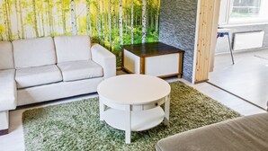 Una sala de estar moderna con un sofá, una mesa redonda de centro y un mueble pequeño.