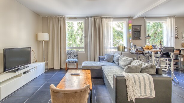 A modern living room with a flat-screen TV, a wooden coffee table, a grey sofa, and a dining area with a table and chairs. - Apartment 'Bel Appartement Bordeaux Centre' with Wi-Fi and Air Conditioning (Bordeaux)