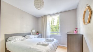 A bedroom with a bed, bedside table, lamp, window, and a cabinet. - Apartment 'Bel Appartement Bordeaux Centre' with Wi-Fi and Air Conditioning (Bordeaux)