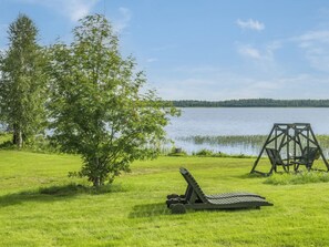 A grassy area with a swing set and a reclining chair by a lake. - Mansikkaranta 1 by Interhome (Pyhäjärvi)