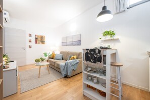Un salon moderne avec un canapé, une table basse, une bibliothèque et un luminaire suspendu.