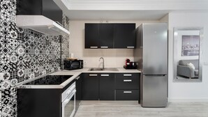 Una cocina moderna con gabinetes negros, un refrigerador de acero inoxidable, un microondas y un lavamanos.