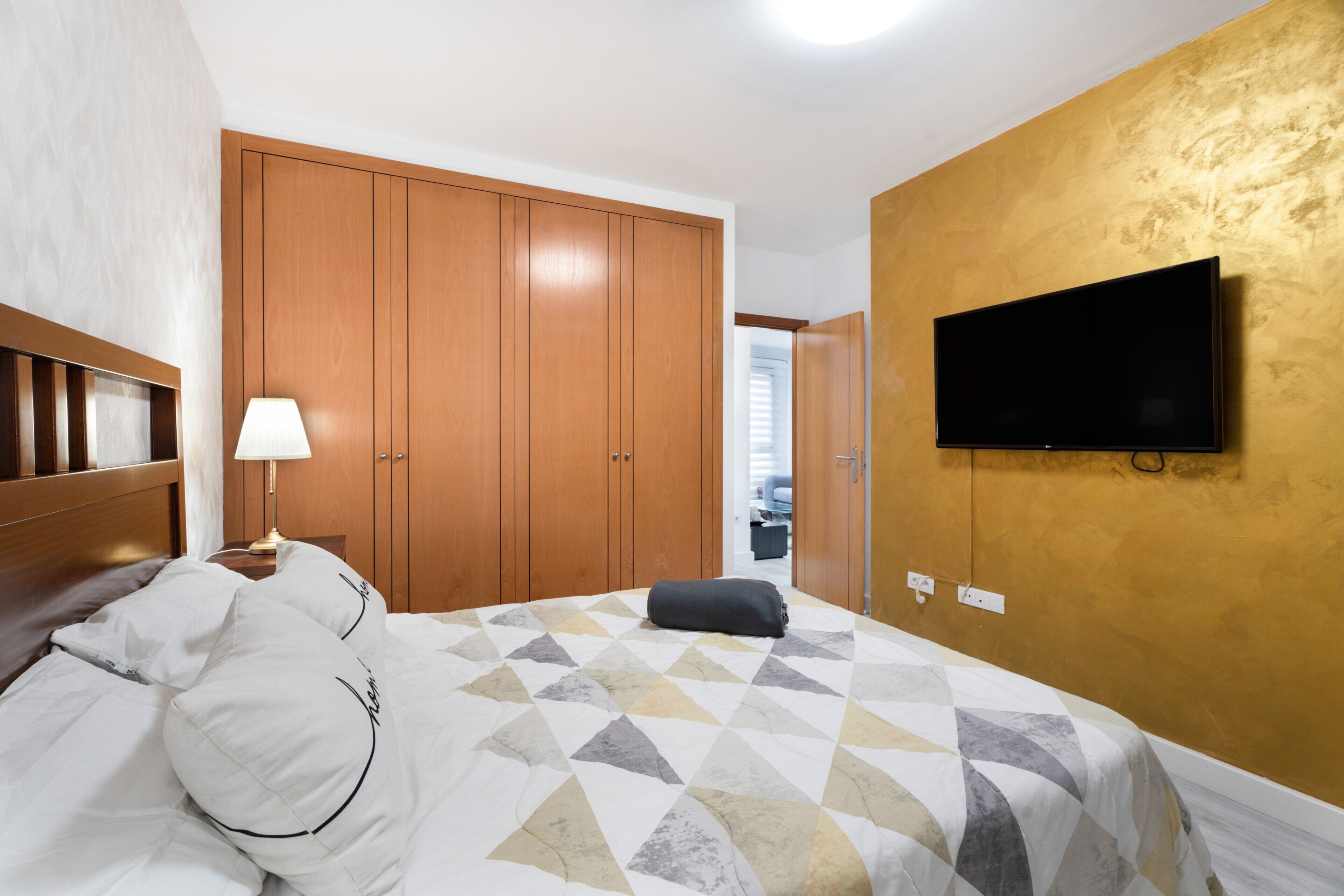 Een hotelkamer met een bed, een aan de muur bevestigde televisie en een kledingkast.