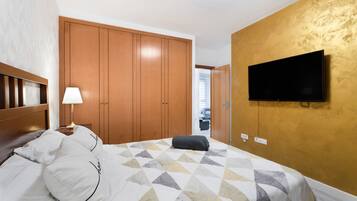 Een hotelkamer met een bed, een aan de muur bevestigde televisie en een kledingkast.