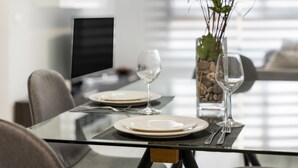 Una mesa de comedor con platos, cubiertos y copas de vino dispuesta para dos personas.