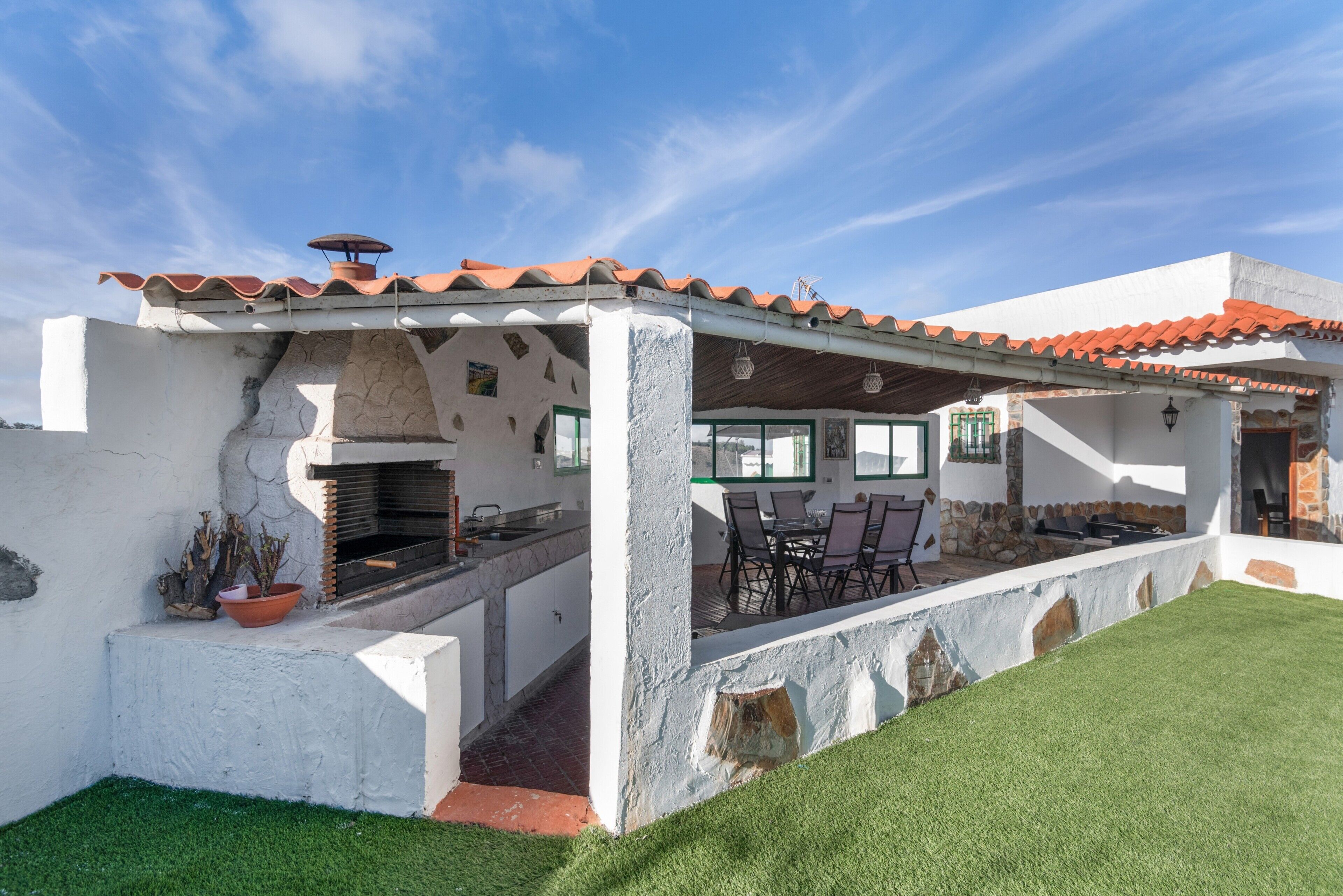 A patio with a grill, outdoor seating, and a white exterior wall.