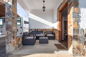 Een patio met stenen muren, buitenmeubilair, een deurmat en een hanglamp.