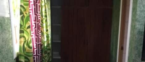 A hallway with patterned curtains, a wooden door, and a green carpet.