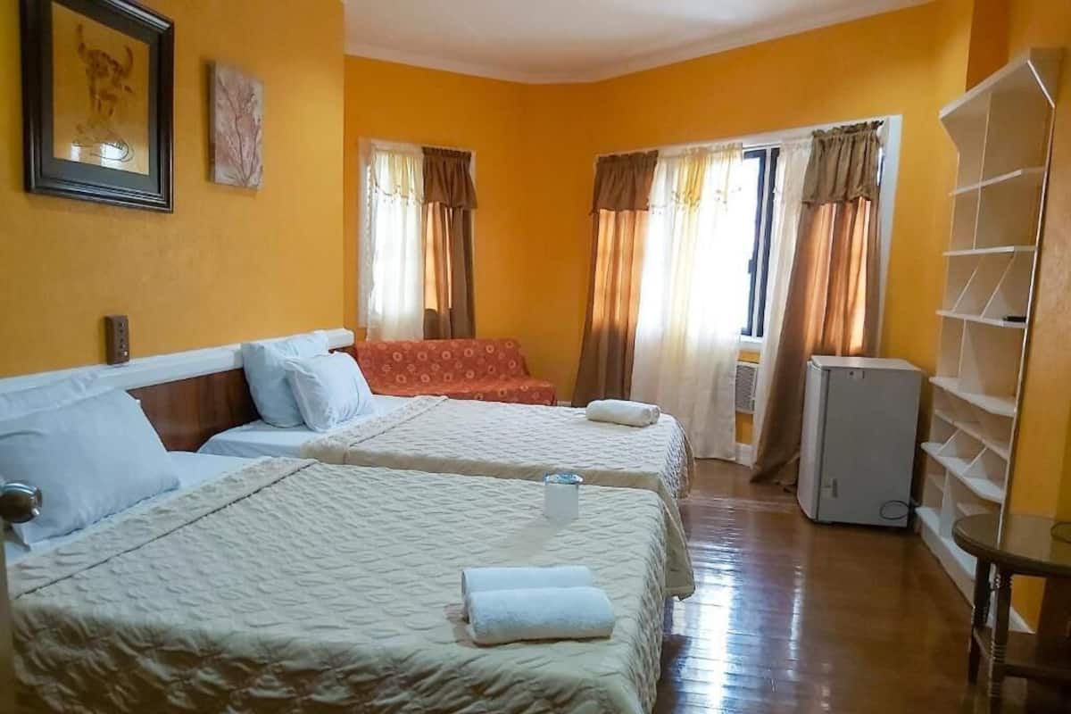 A hotel room with two beds, a wardrobe, and a small table.