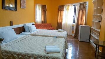 A hotel room with two beds, a wardrobe, and a small table.