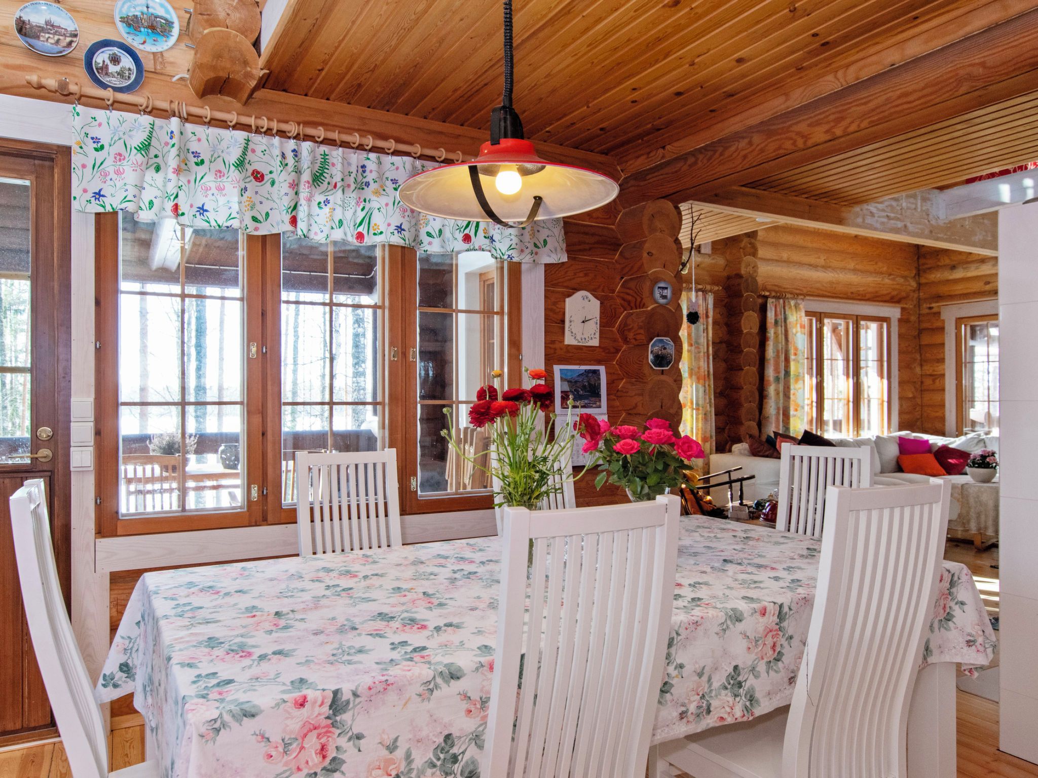A wooden interior with a dining table, chairs, and a hanging light fixture.