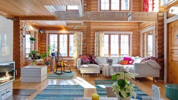 A log cabin interior with a fireplace, sofas, and a dining area.