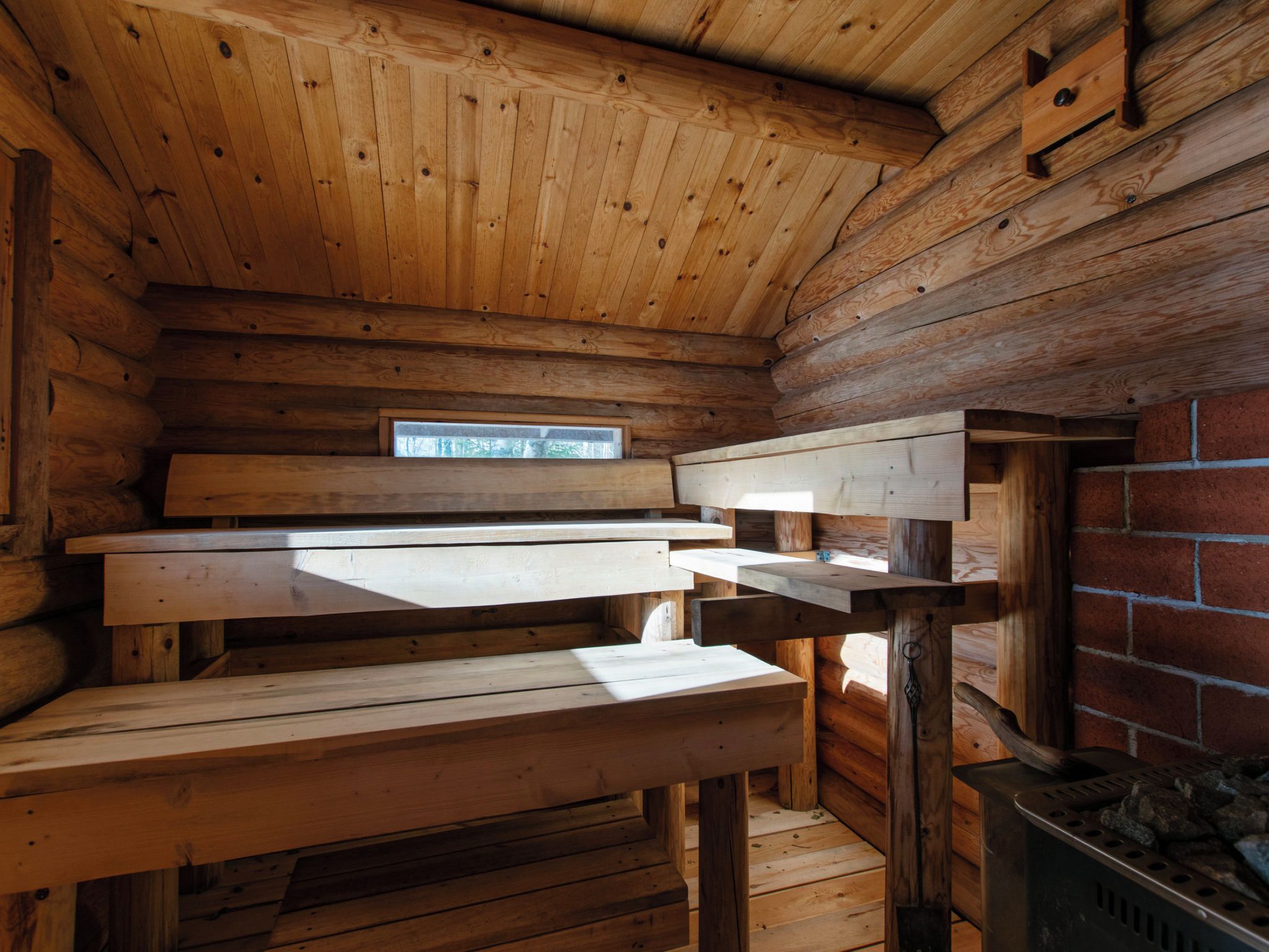 L’intérieur d’une cabane en rondins, avec un banc en bois, une petite table et une fenêtre.
