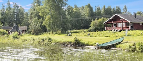 A lakeside cabin with a dock and a swing set.