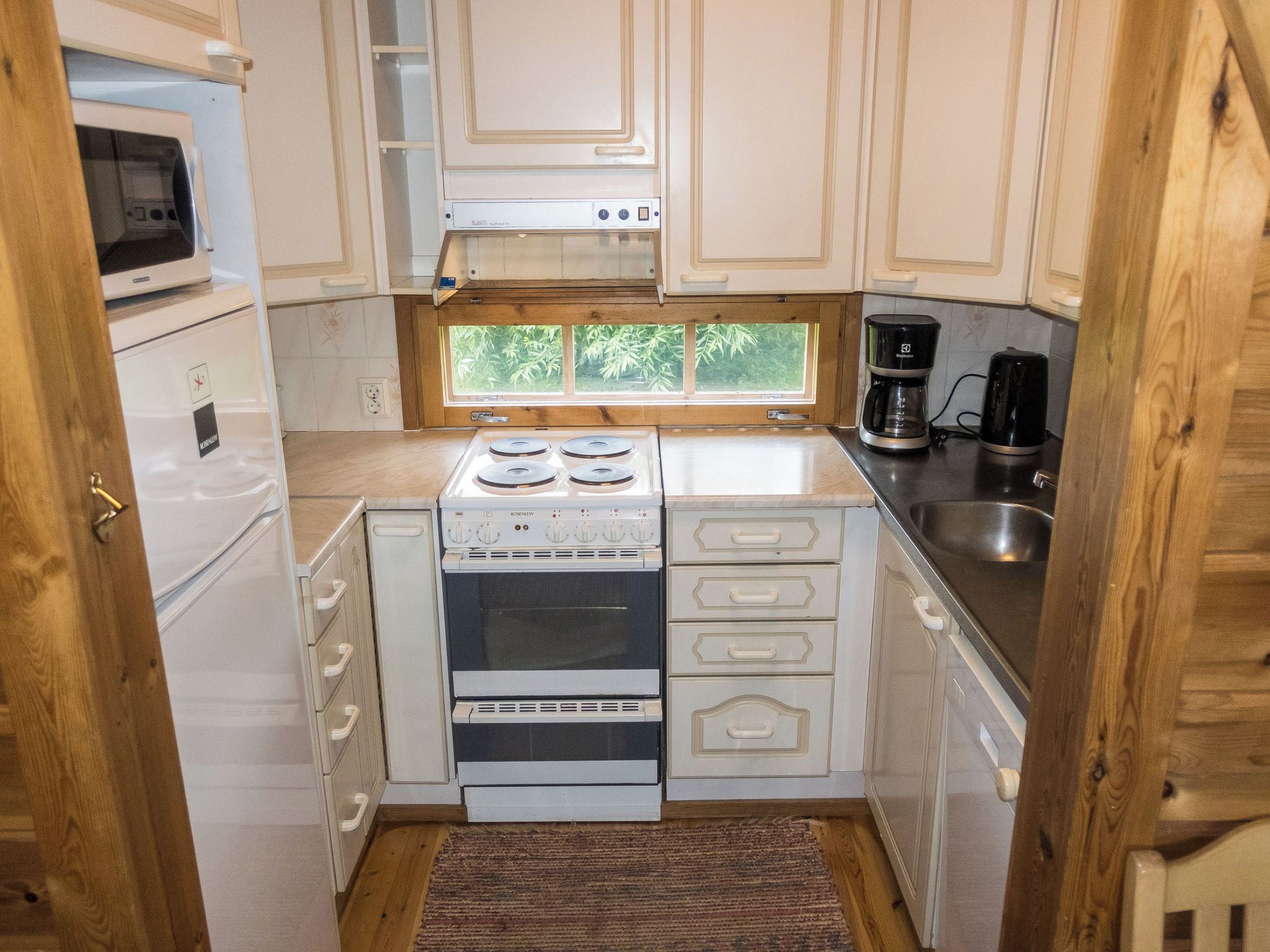 A compact kitchen with a microwave, stove, oven, and a coffee maker.
