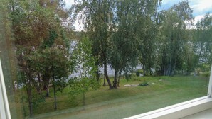 A view from a window overlooking a grassy area with trees and a body of water. - Budget Double or Twin Room - Lapin Satu Hotel (Lapland)