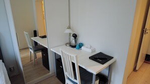 A compact hotel room with a white desk, a chair, a lamp, a coffee maker, a remote control, and a trash bin. - Budget Double or Twin Room - Lapin Satu Hotel (Lapland)