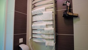 Une salle de bain équipée d’un porte-serviettes sur lequel sont disposées plusieurs serviettes blanches, de toilettes et d’une prise électrique murale.