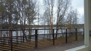 A view from a balcony with a wooden railing overlooking a lake surrounded by trees. - Superior Double or Twin Room with Terrace - Lapin Satu Hotel (Lapland)
