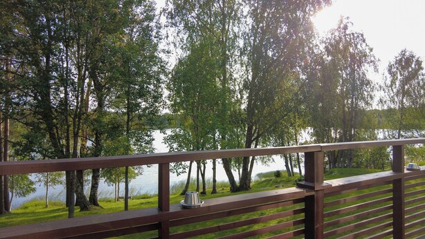 A wooden deck overlooking a lake with trees and grassy areas. - Superior Double or Twin Room with Terrace - Lapin Satu Hotel (Lapland)
