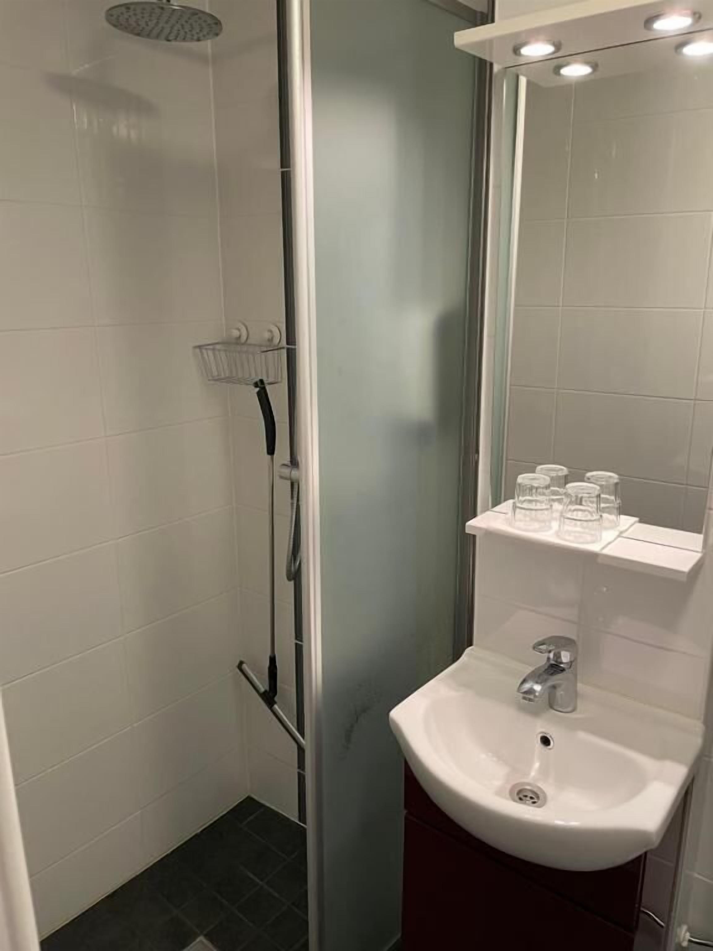 Un baño moderno con cabina de ducha de vidrio, un lavabo blanco y un espejo sobre el lavabo.