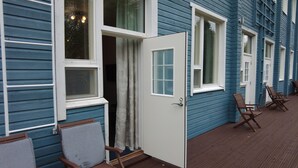 Un edificio azul con detalles blancos, una puerta y una ventana. Hay sillas de madera afuera.
