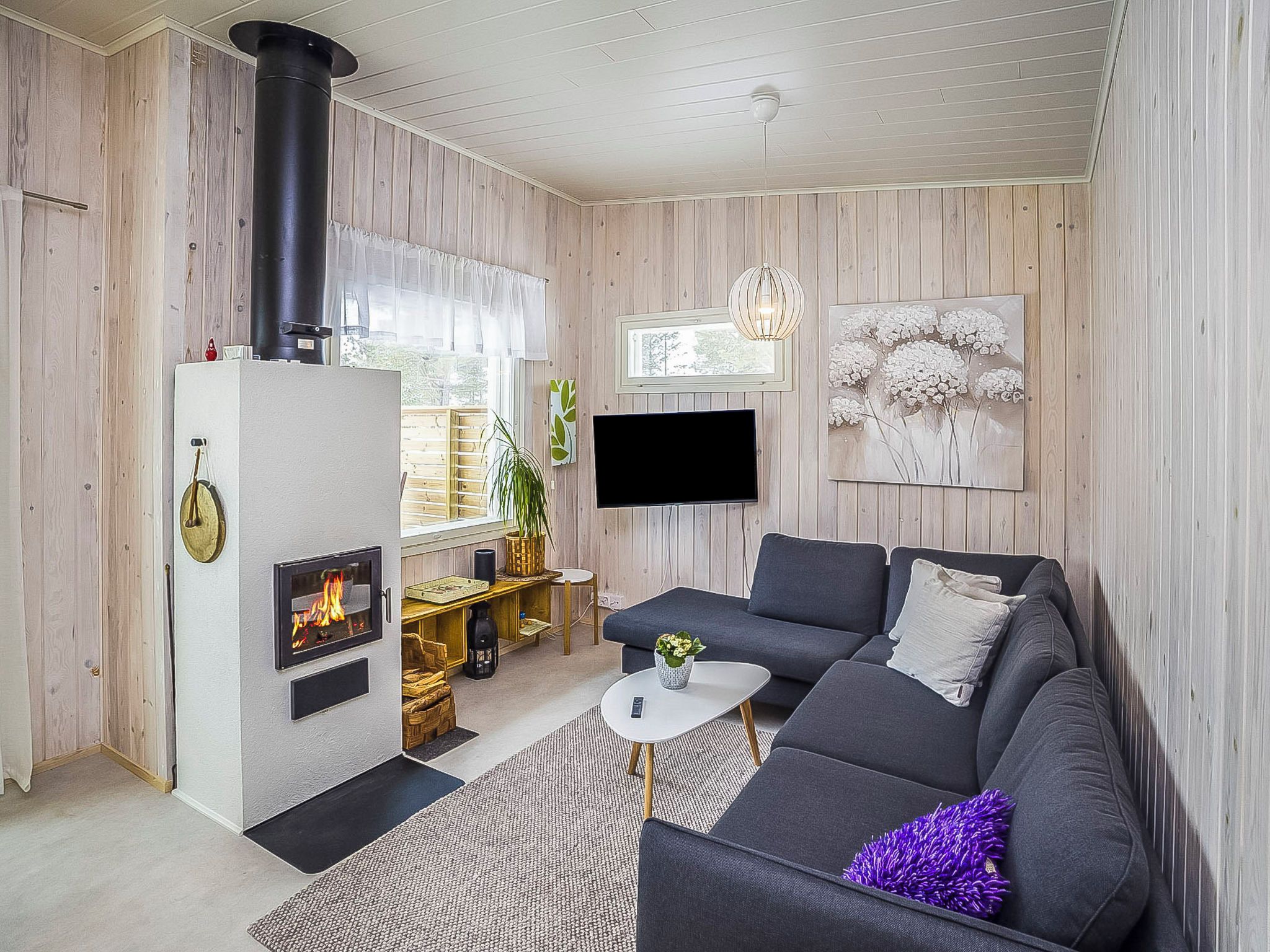 A modern living room with a fireplace, a sofa, a coffee table, and a TV mounted on the wall.