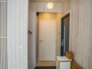 A hallway with a white door, a wooden cabinet, and a hanging light fixture.